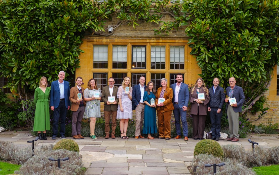 Group of award recipients standing in front of a building covered in greenery.