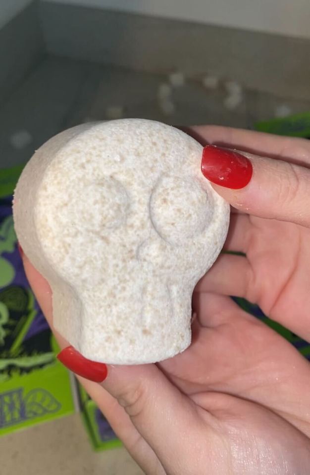 A person holding a sugar skull shaped bath bomb.