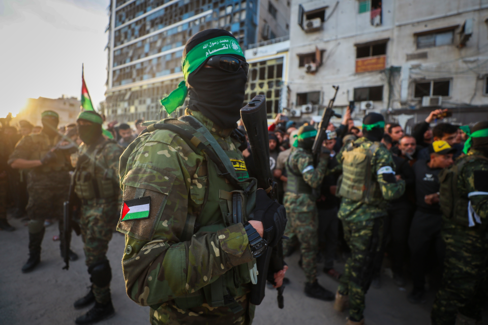 Fighters from the Qassam Brigades control a crowd as the Red Cross collects Israeli hostages in Gaza City.