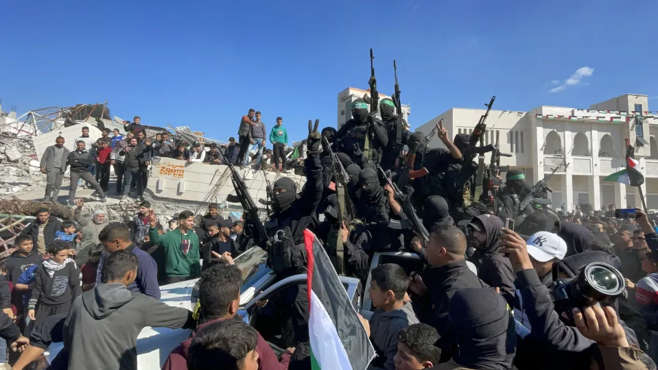 Militants and civilians gather as Hamas and Islamic Jihad militants keep guard while standing among rubble in Gaza City.