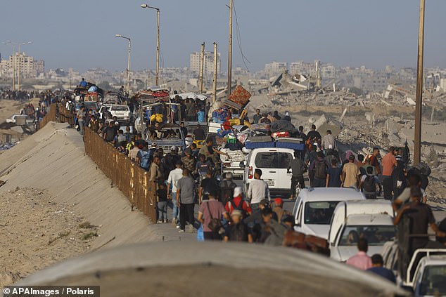 Displaced Palestinians walk with their belongings along the coastal road towards Gaza City