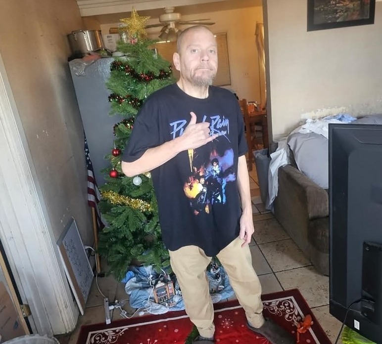 A man standing by a decorated Christmas tree.