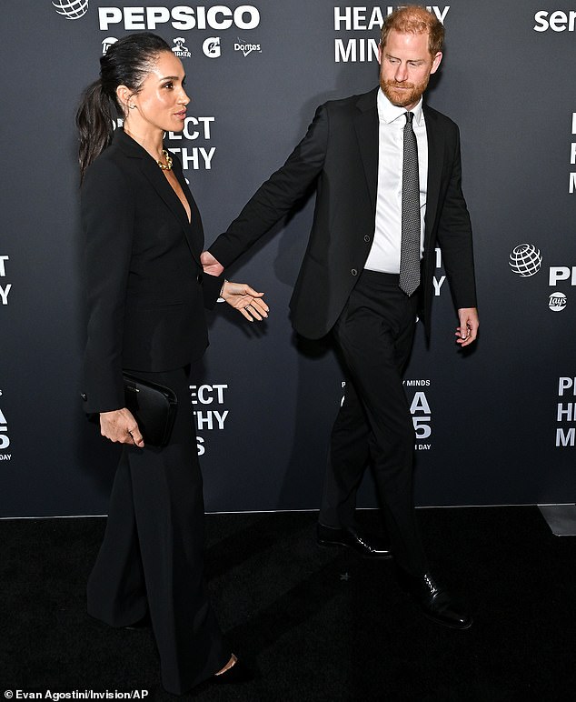 But at one point, the Duke of Sussex appeared to hurry his wife along as they paused for a brief photo session on the red carpet and Meghan was also left alone as Harry held a conversation a distance away