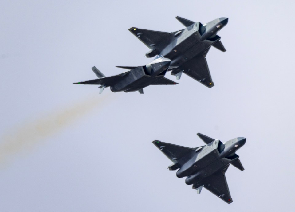 Three J-20 stealth fighter jets performing in the sky.