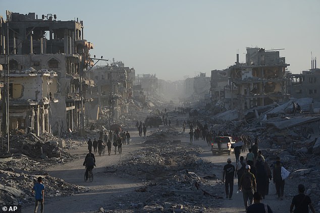 Displaced Palestinians carry their belongings as they walk along the heavily damaged Al-Jalaa Street in Gaza City this morning