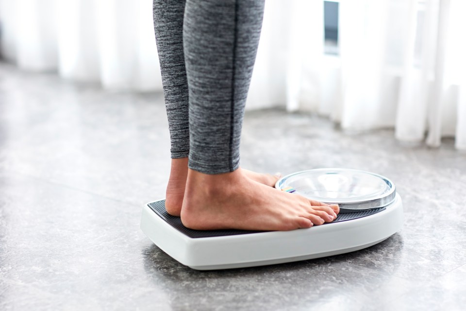 Young woman's bare feet stepping on a bathroom scale.