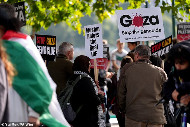 People hold signs reading 'Stop the genocide' as they protest in support of Palestinians today