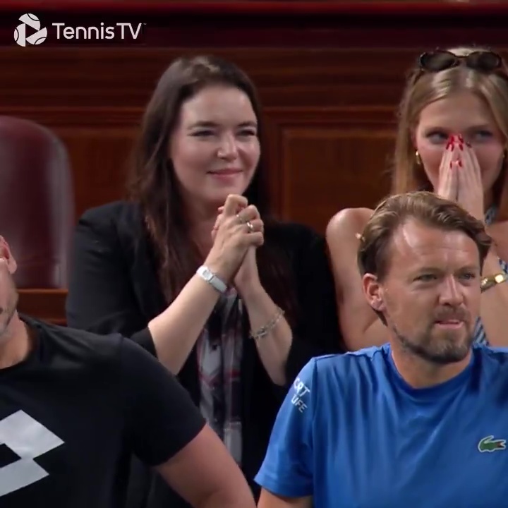 A woman smiling and clapping, with two men and another woman in the audience.