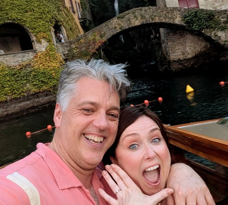 Iain Lee and his now-fiancée smiling and showing off her engagement ring.