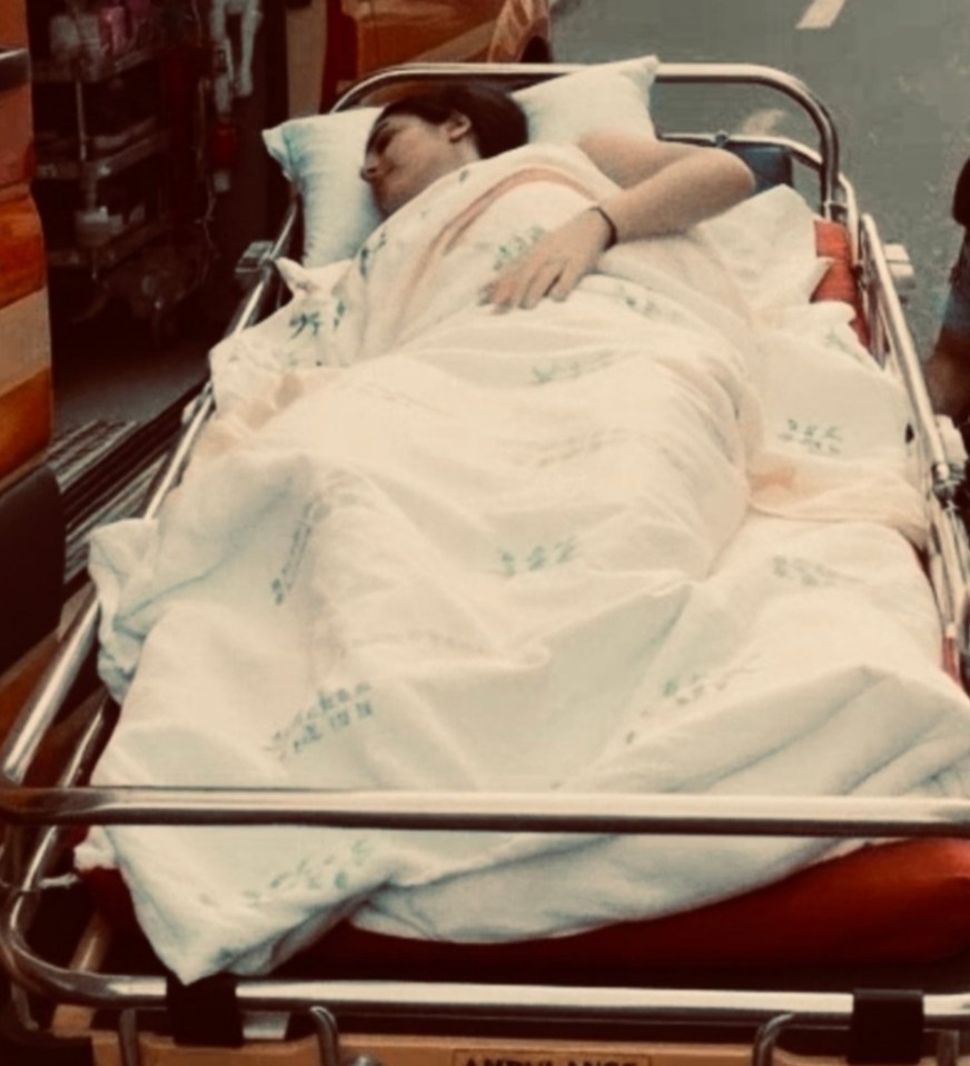 A person lying on an ambulance stretcher.
