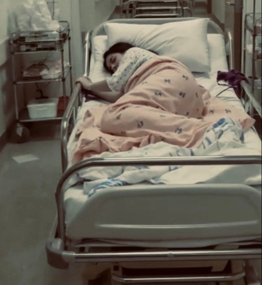 A woman lying on a gurney in a hospital hallway.