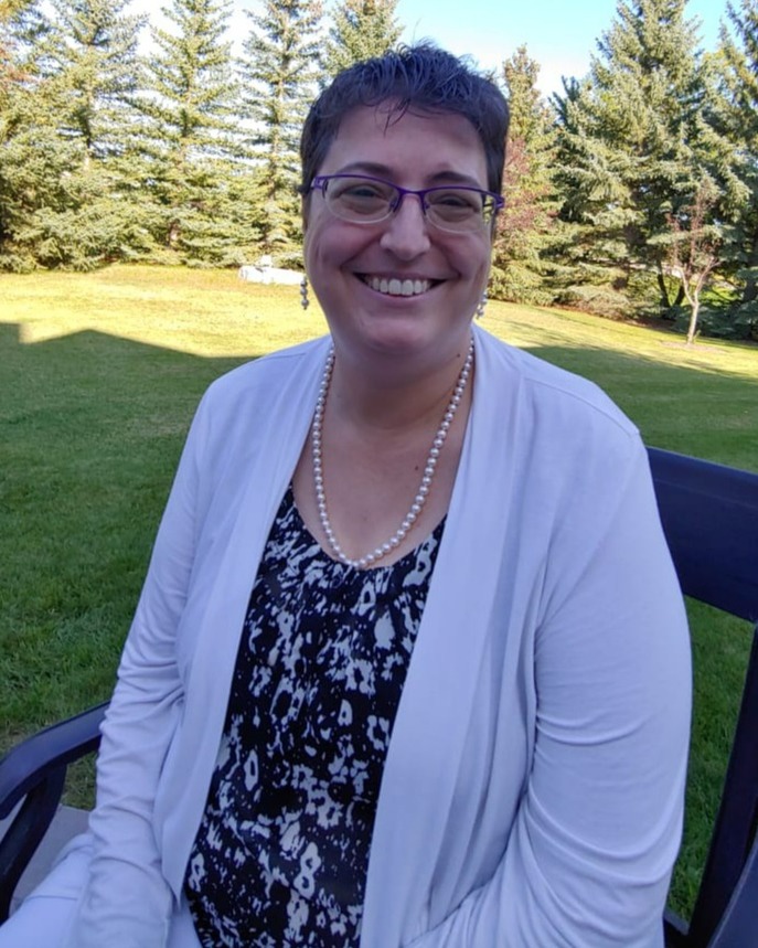 Cindy Buckshon smiling in a white cardigan and patterned shirt.