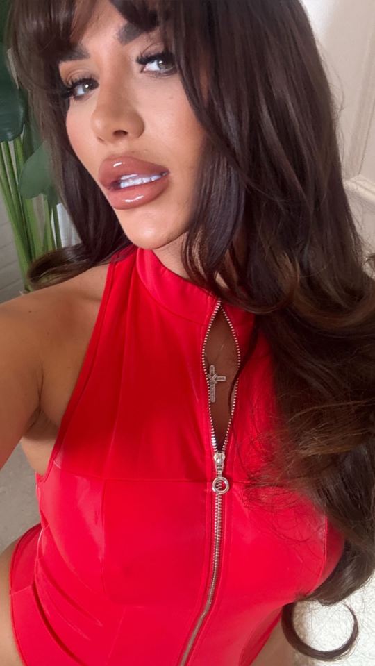 Chloe Brockett in a red zippered outfit, with a cross necklace visible.