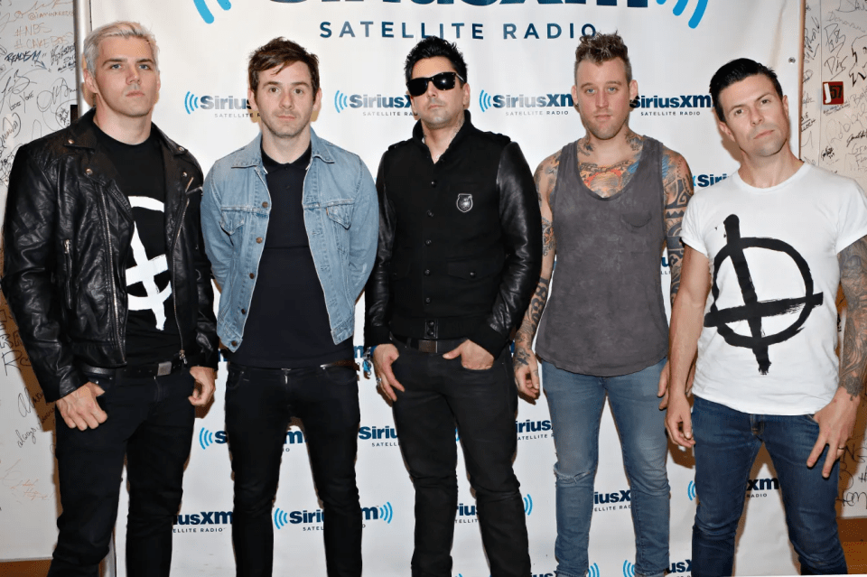 Five male band members pose in front of a SiriusXM Satellite Radio banner.