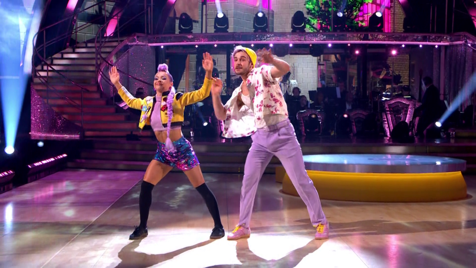 Two dancers on a stage with a band in the background.