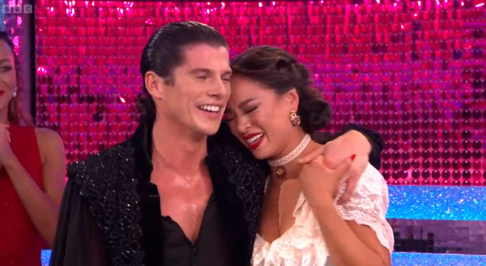 A man and a woman embracing and laughing on a stage.