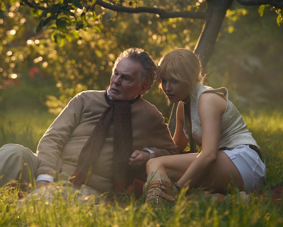 Derek Jacobi and Ellie Bamber sitting in a garden during golden hour.