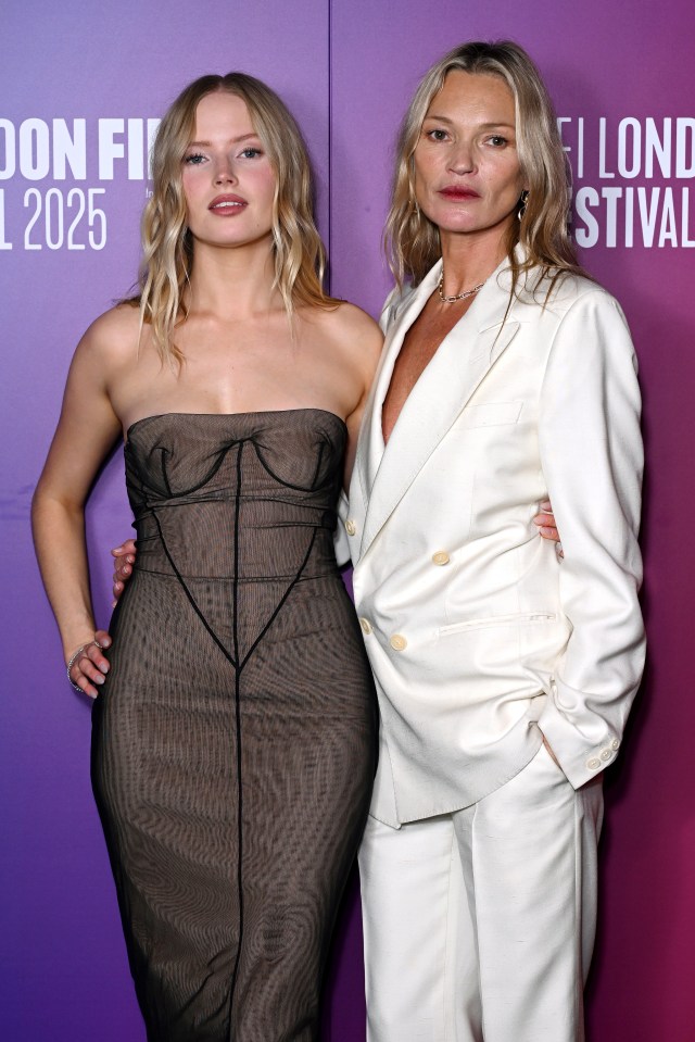 Ellie Bamber in a black strapless dress and Kate Moss in a white suit pose together.