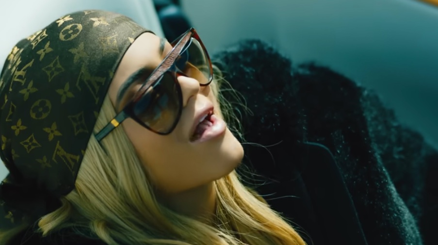 Woman in sunglasses and a Louis Vuitton scarf.