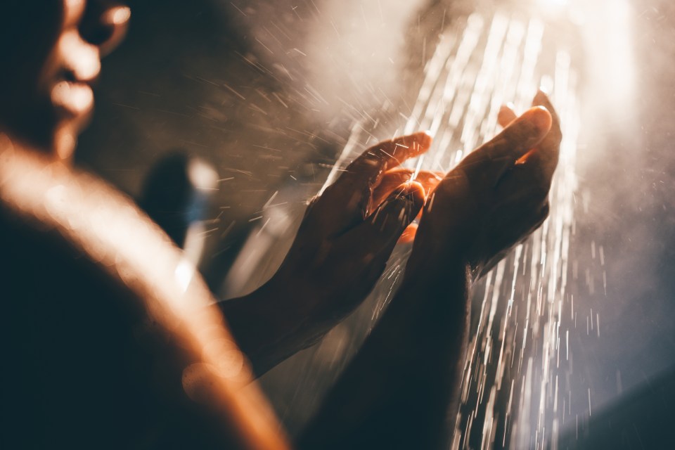 Woman washing her hands under a shower.