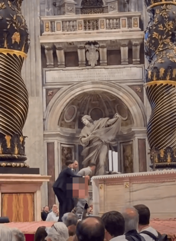 Man urinating on an altar at St. Peter's Basilica while being restrained by another man.