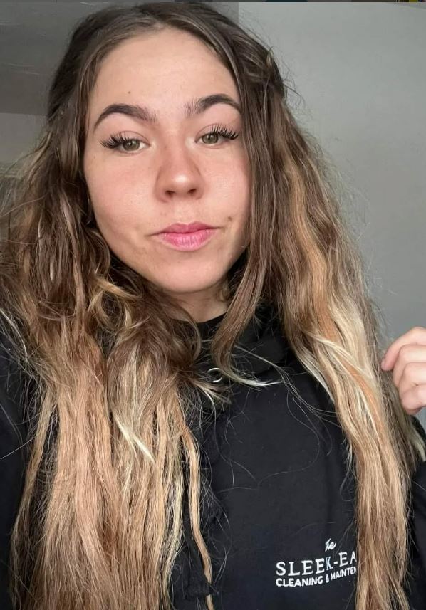 Laura, an employee of Sleek-Easy Cleaning & Maintenance, wearing a black hoodie with the company logo.