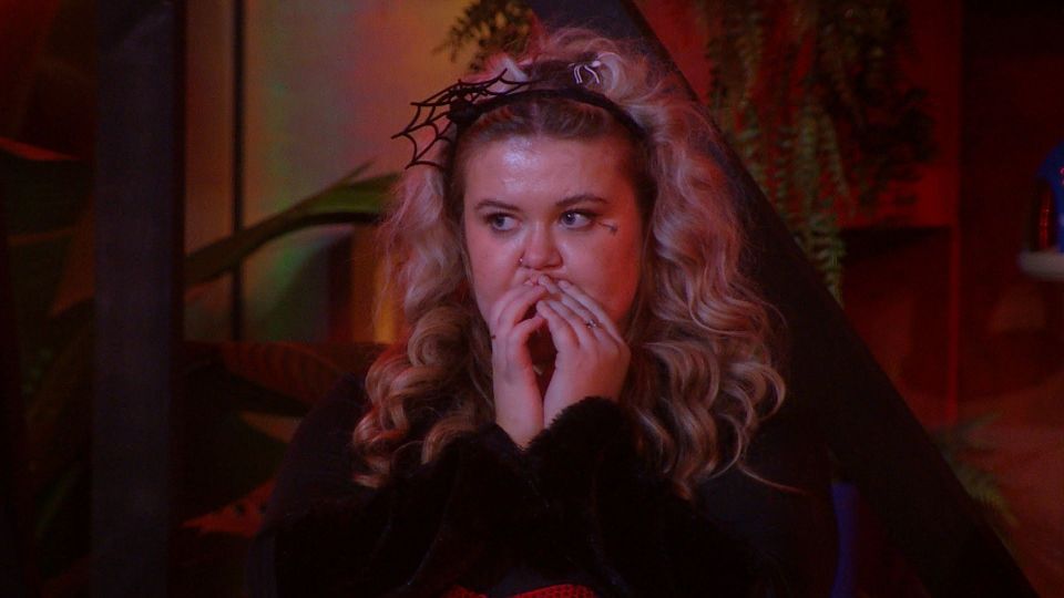 Martha on Big Brother, wearing a spiderweb headband, with her hands covering her mouth.