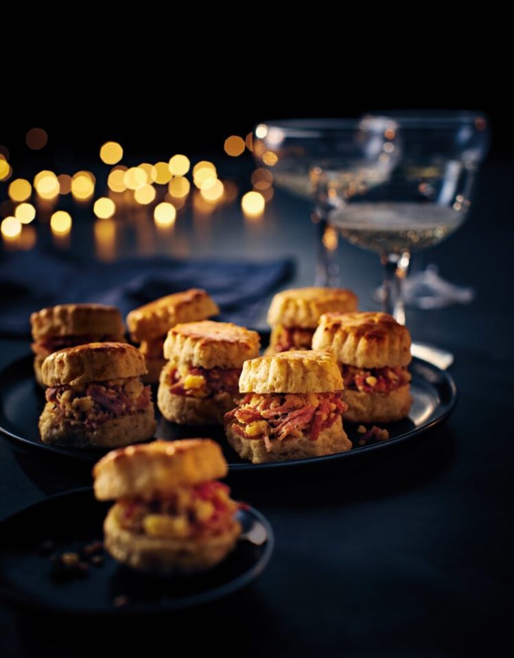 Scones filled with what appears to be shredded pork and pineapple, with champagne glasses in the background.