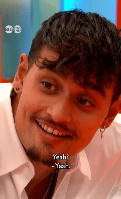 A man with dark curly hair and a mustache smiles, with "Yeah?" and "- Yeah." subtitles.