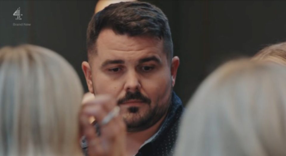 A man looks down with a concerned expression, visible between the backs of two women's heads.