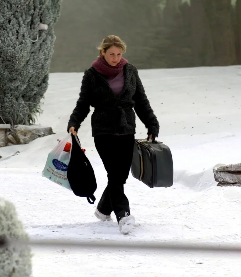 Renée Zellweger as Bridget Jones carrying a bag and suitcase in the snow for "Bridget Jones's Diary".
