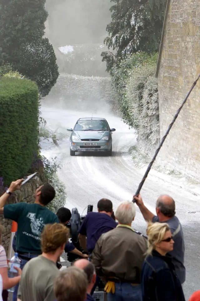 A green car driving down a snow-covered village road during filming for Bridget Jones's Diary.