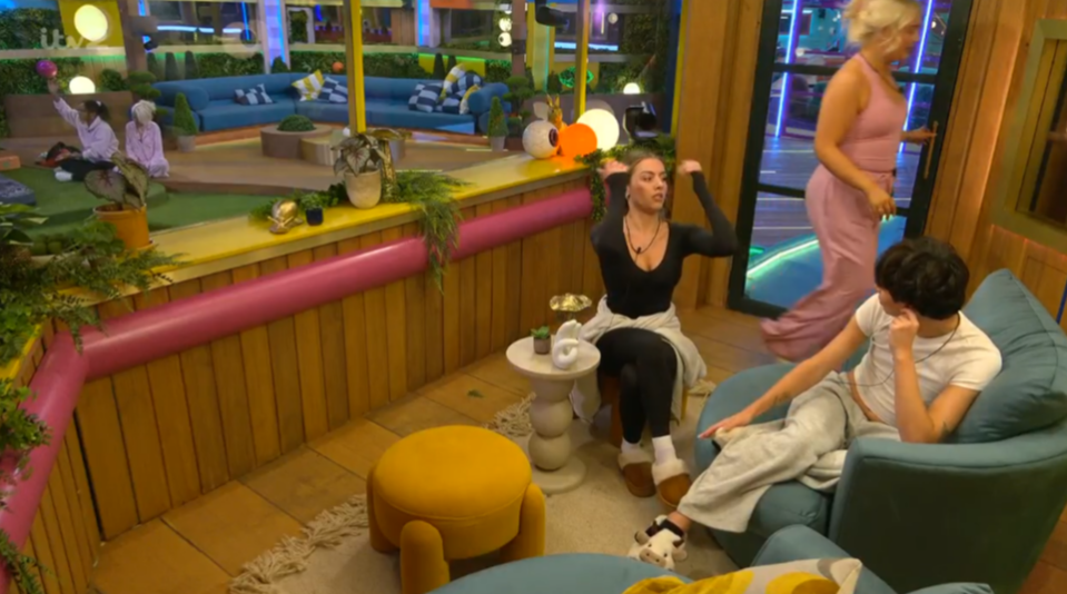 A group of people relaxing in a colorful, modern room with plants and large windows.