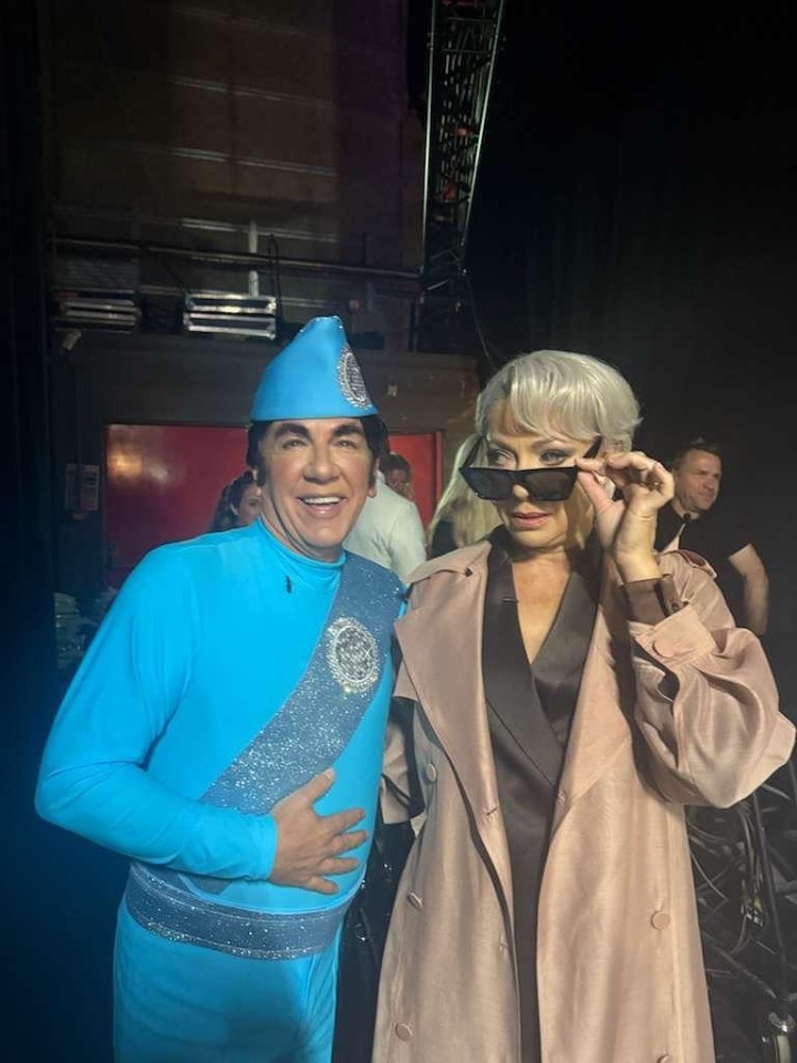 Ross King in a blue costume with a woman in a trench coat.