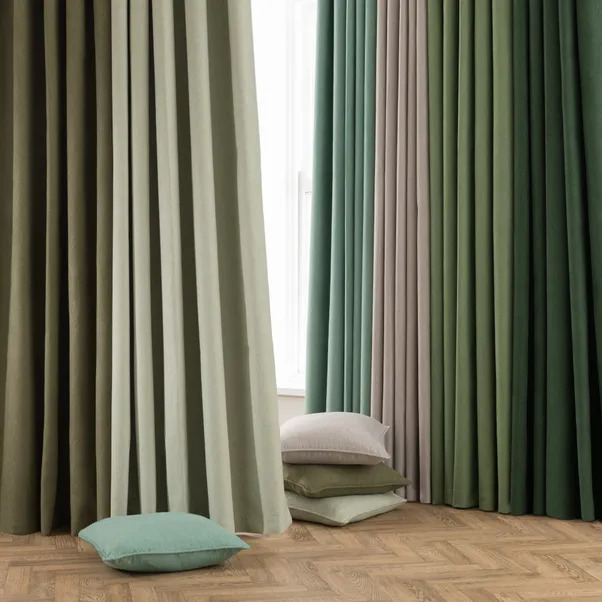 Multiple colored curtains and pillows on a wood floor.