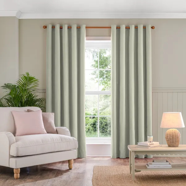 A pair of light green eyelet curtains hanging in a window.