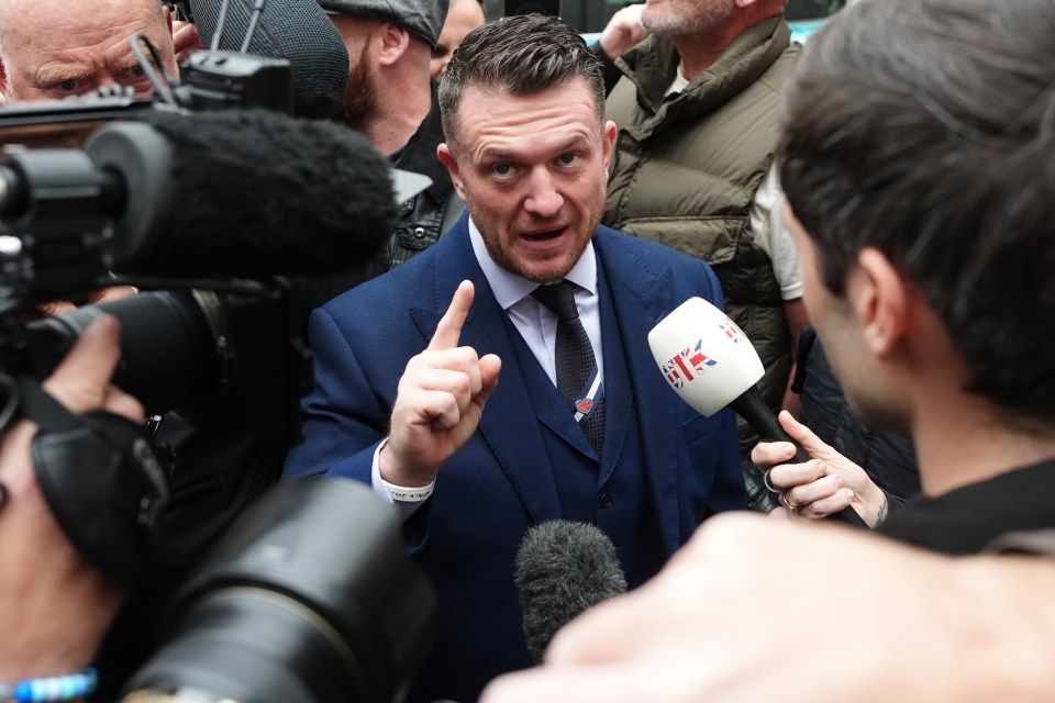 Stephen Yaxley-Lennon (Tommy Robinson) speaks into multiple microphones while surrounded by cameras and people.