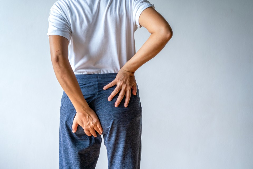Woman from behind holding her buttocks, indicating abdominal pain or hemorrhoids.