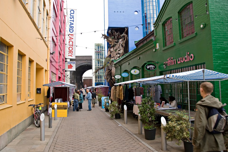 A street market at the Custard Factory in Birmingham, with stalls lining a paved walkway.
