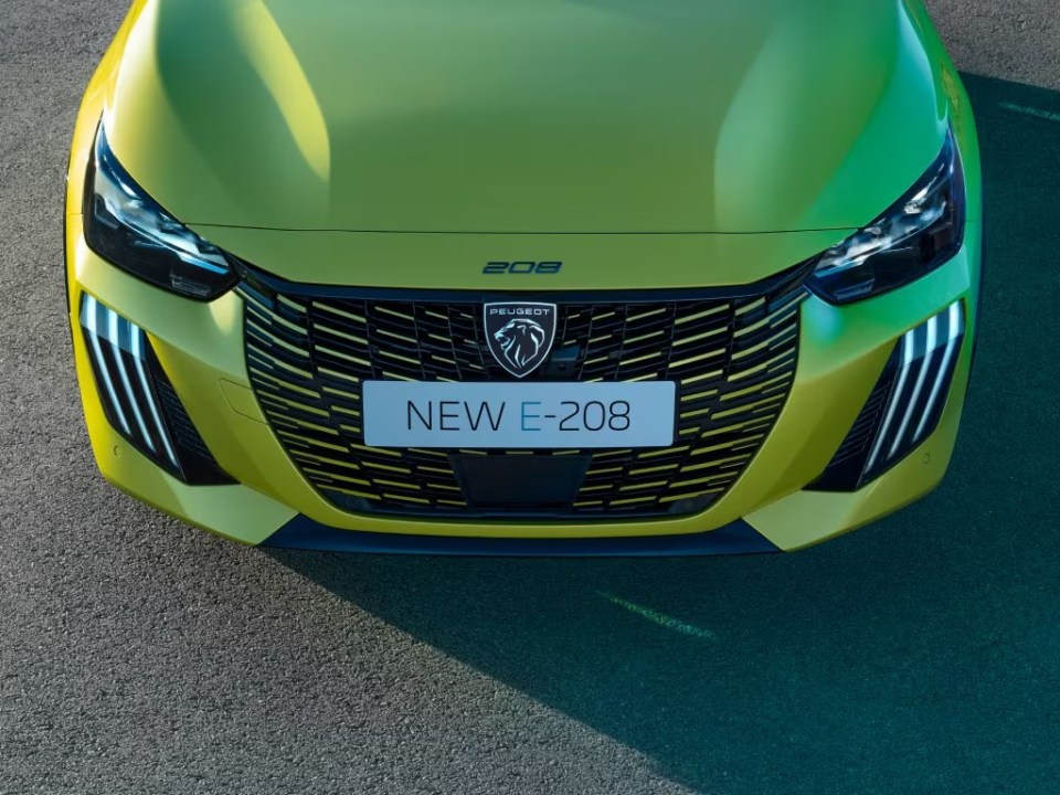 Front view of a yellow Peugeot E-208 car with the "NEW E-208" license plate.