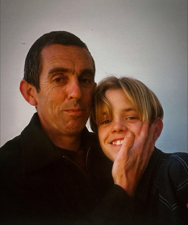 A man and a boy smiling with their heads close together, the man's hand on the boy's cheek.