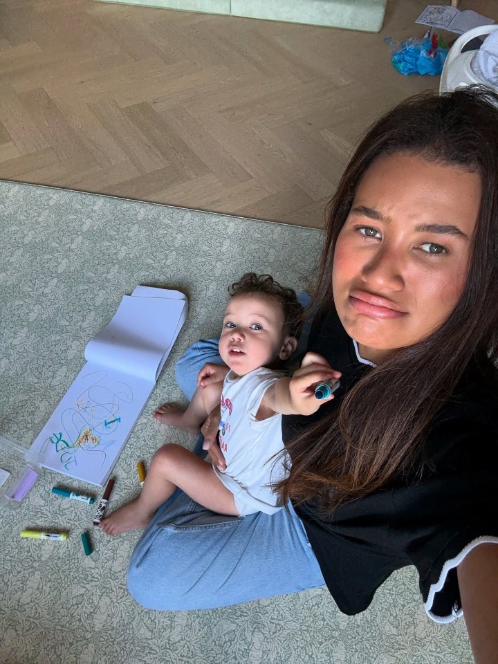 Montana Rose Brown holding a baby with drawing materials around them.