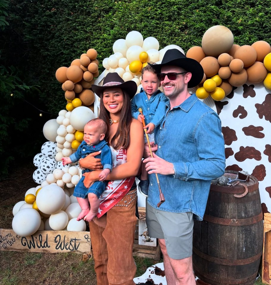 Family of four in cowboy attire posing in front of a "Wild West" backdrop with balloons.