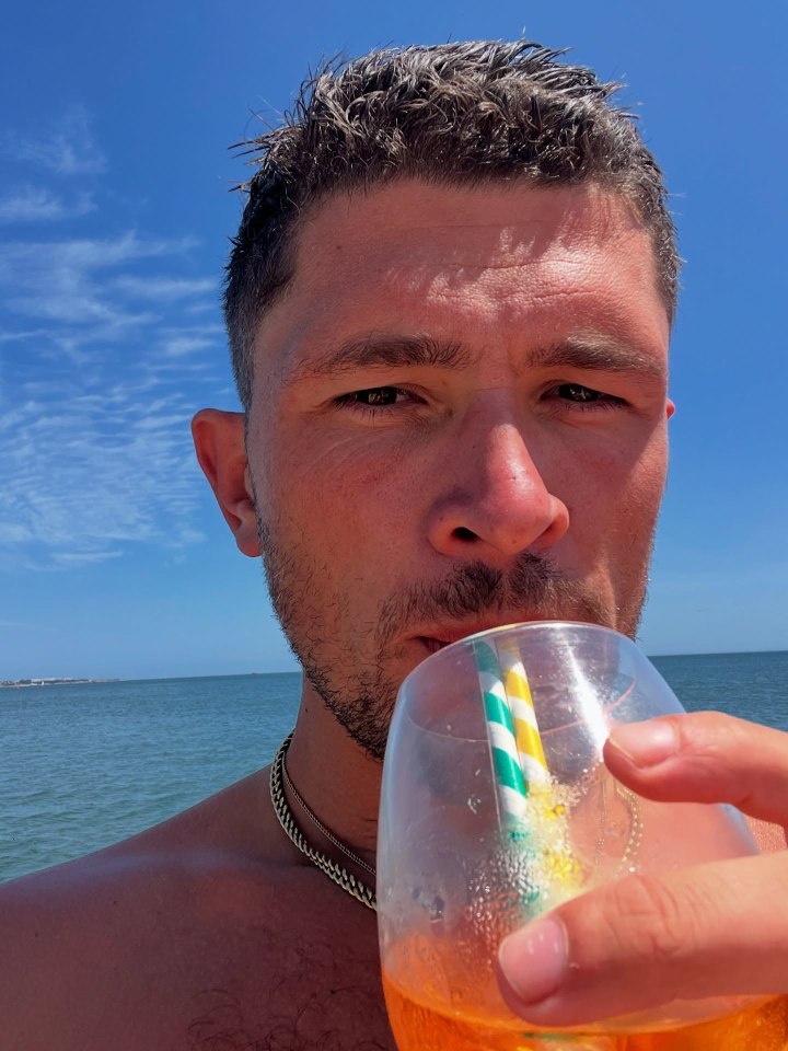 Jordan Davies drinking from a glass with a straw while in the ocean.