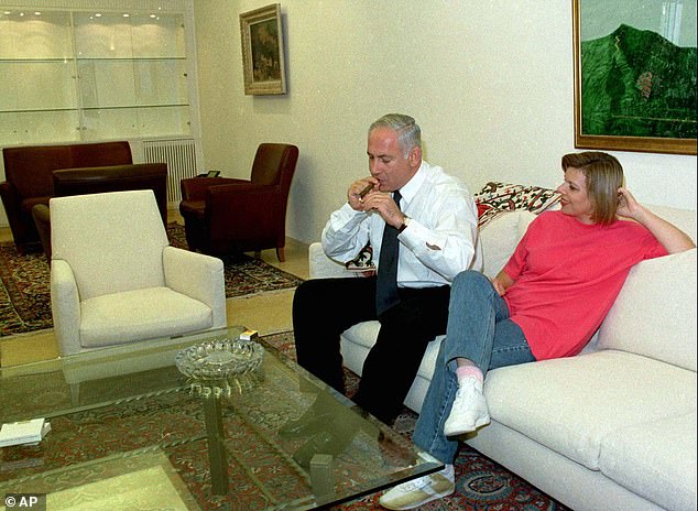 Sarah Netanyahu watches her husband, Israeli Prime Minister Benjamin Netanyahu, light a cigar at their home in Jerusalem in 1997