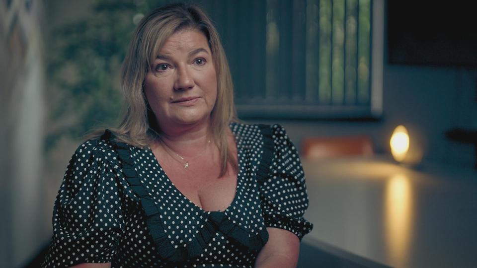 Speaker presenting on stage to an audience in a darkened room, with a screen displaying "PROGRAM YOURSELF FOR SUCCESS"