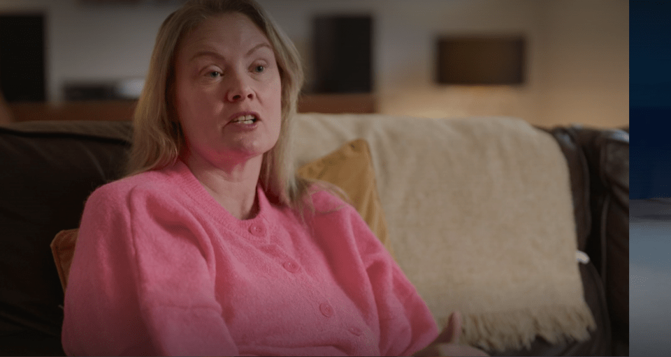 Speaker presenting on stage to an audience in a darkened room, with a screen displaying "PROGRAM YOURSELF FOR SUCCESS"
