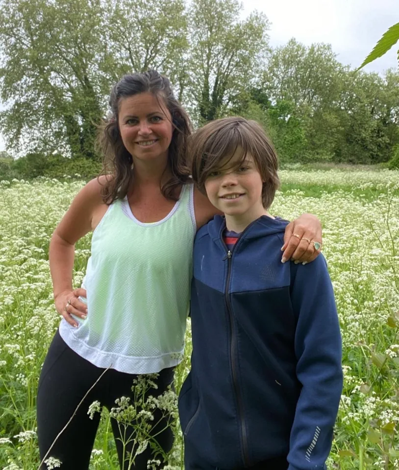 Deborah James with her son in a field of white flowers.