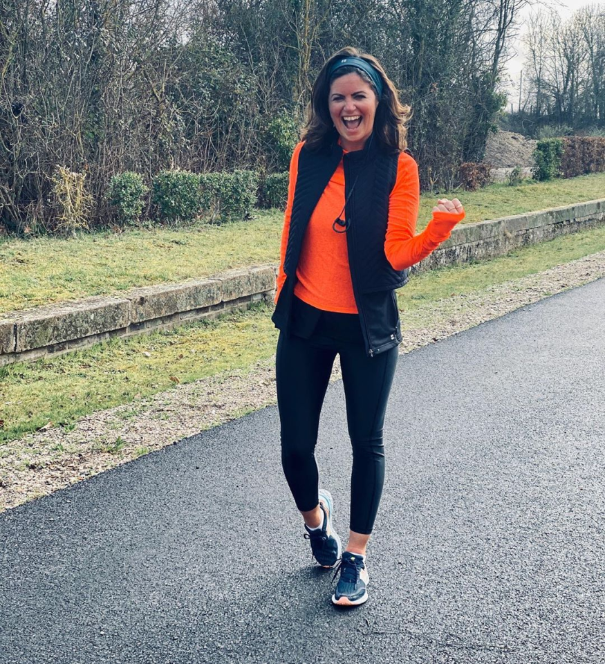 Deborah James walking outdoors in athletic wear, smiling with her mouth open and arm raised.