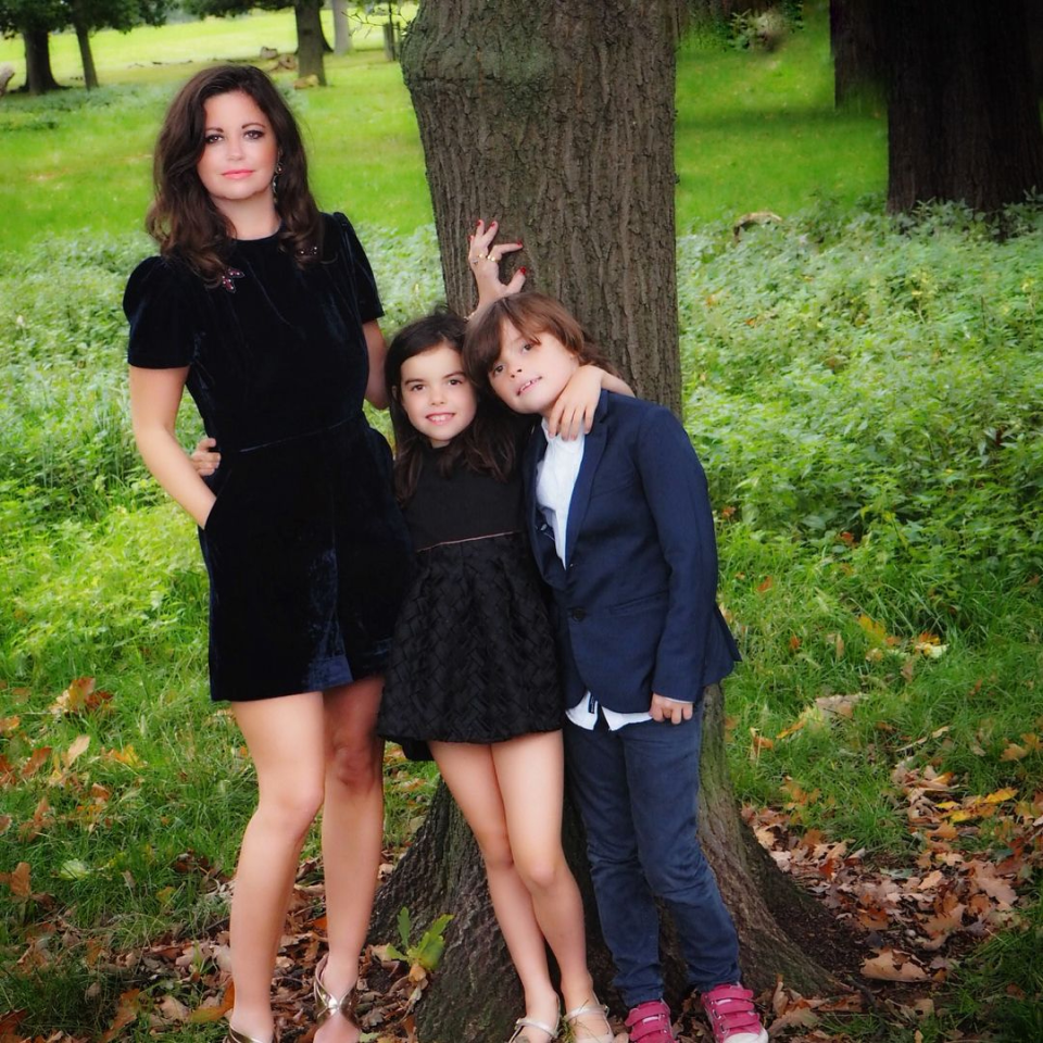 Deborah James posing with her children by a tree.